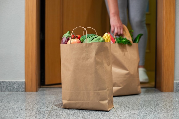 A woman picks up a bag of food at the door of her house. Coronavirus. Quarantine. Stay at home, Online shopping. Vegetables and fruits delivery during quarantine and self-isolation