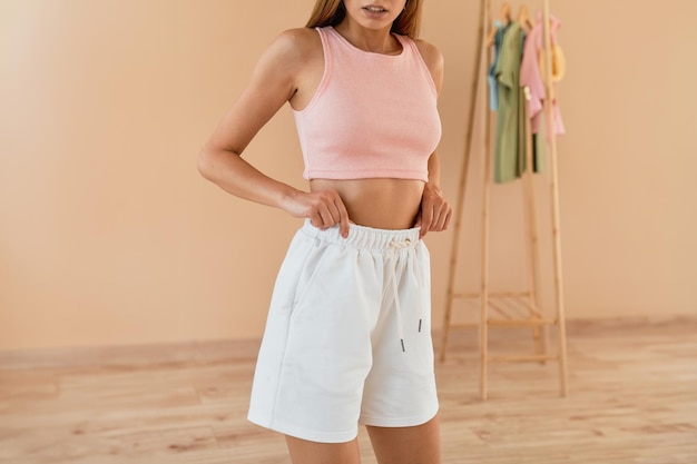 Photo a woman in a pink crop top and white shorts smiles brightly in a studio setting she looks fit and happy as she poses for the camera horizontal studio photo