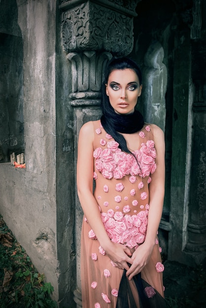 woman in a pink dress and a black veil near the tomb in the cemetery