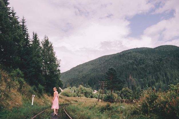 Photo woman in pink dress walking on railroad tracks