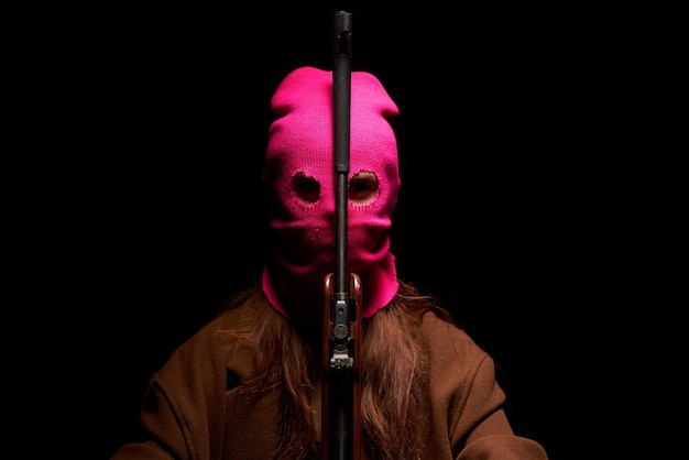 Woman in a pink mask the gun crime gangster danger the dark background