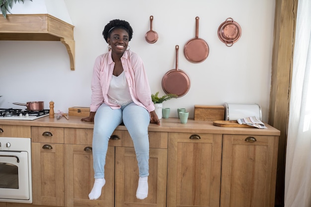 A woman in pink shirt sitting on the table in the kitchen