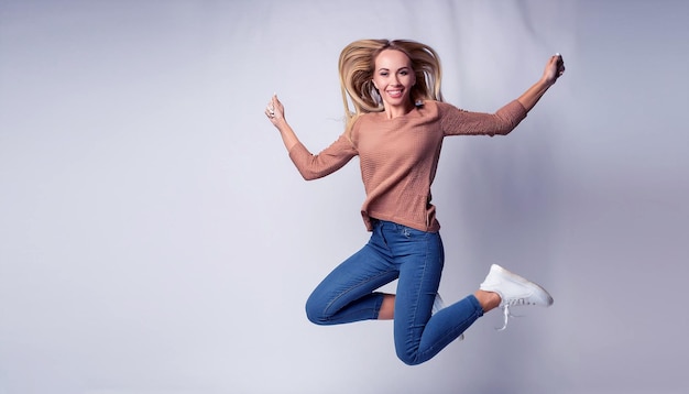 Photo a woman in a pink sweater is jumping in the air with her arms outstretched