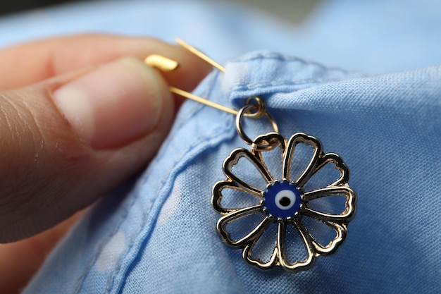 Woman pinning evil eye amulet on clothing closeup