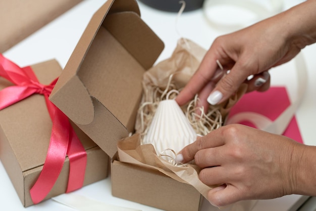 Photo a woman places a box of white chocolates in a box with a red ribbon.