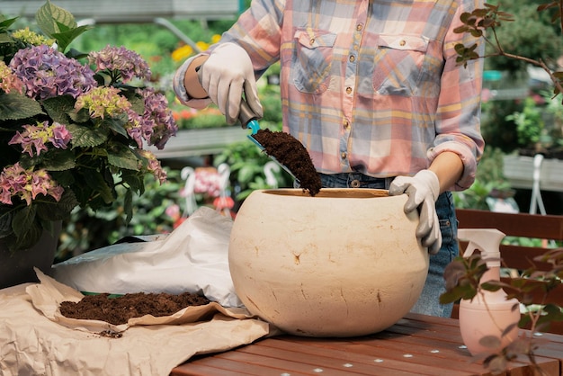 Woman planting flower in pot using dirt in garden center