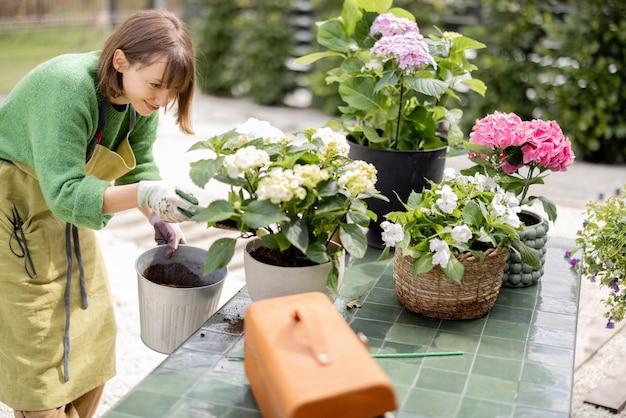 Woman planting flowers into pots on table in garden