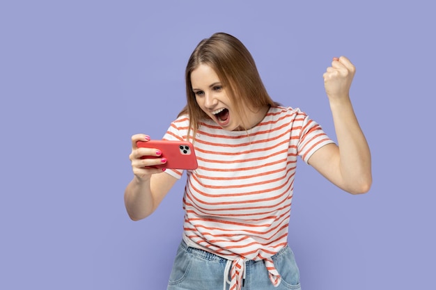 Woman playing game on smart phone winning level clenched fist celebrating her victory