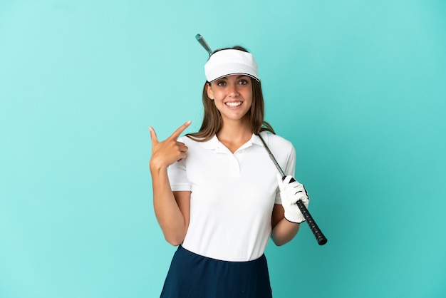 Woman playing golf over isolated blue background giving a thumbs up gesture