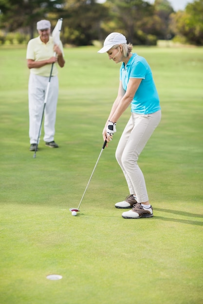 Woman playing golf while standing by man