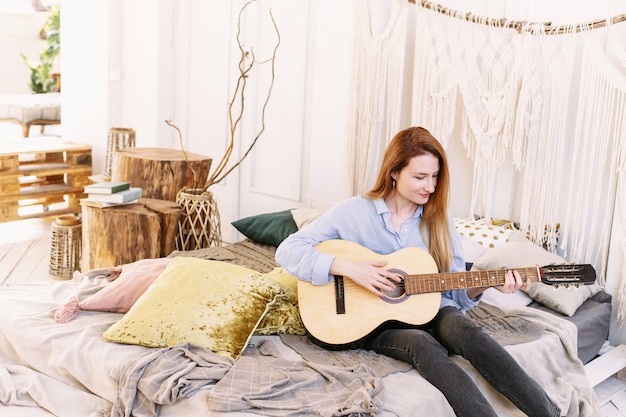 Woman playing the guitar on the bed