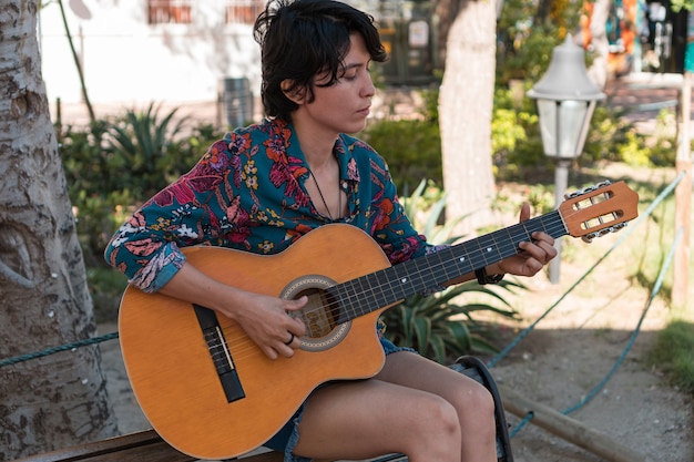 Woman playing guitar sitting on a park