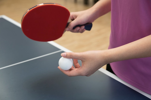 Woman playing table tennis with the racket and ping pong ball in serving position