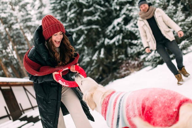 Woman playing with a dog on a snowy street with a red donut