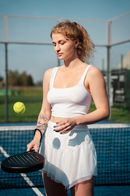 Woman playing with tennis paddle medium shot