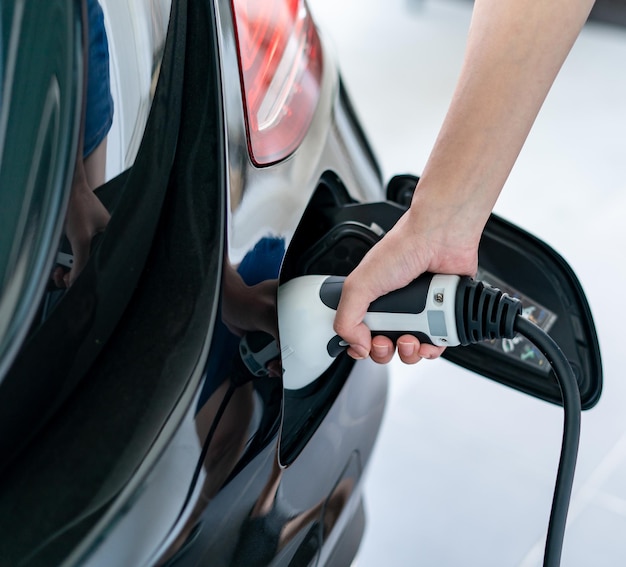 Woman plugged cable charging an electric car at home