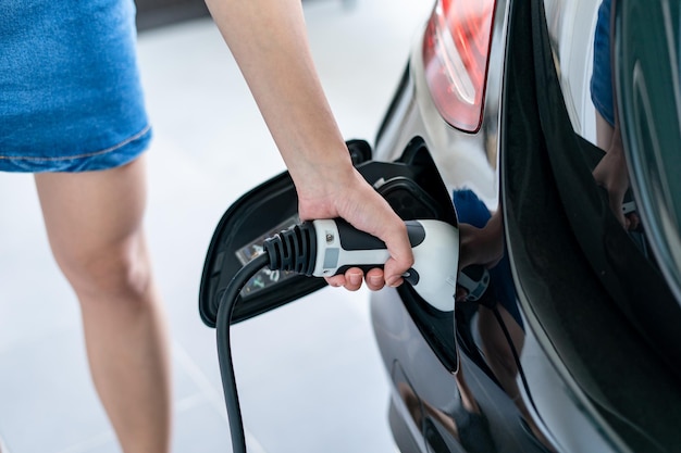 Woman plugged cable charging an electric car at home