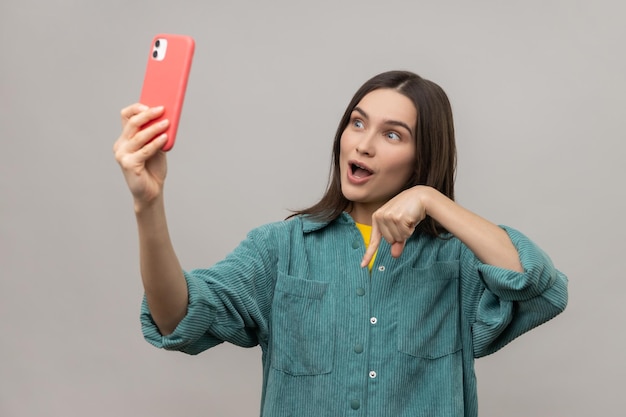 Woman pointing down while communicating by video call or streaming gesturing to subscribe