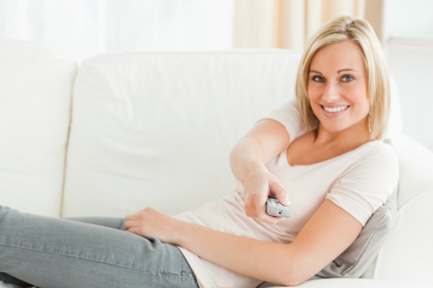 Woman pointing a remote at the camera with a knowing smile