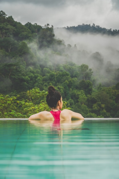 Woman and the pool watching the scene in front of the misty forest