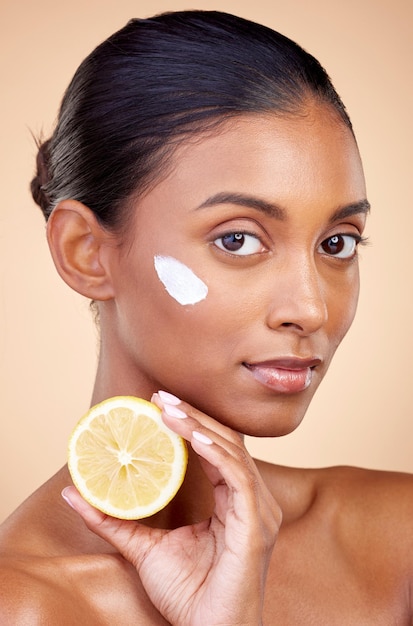 Woman portrait and cream with lemon for skincare cosmetics cleaning and natural beauty product or vitamin c benefits Face of young person with fruits for dermatology on studio brown background