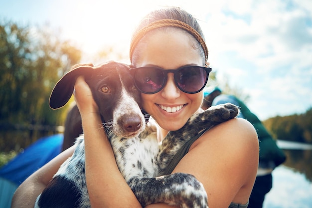 Woman portrait and dog with love for camping in forest sunshine and together for smile by support of adventure time Happy female person and puppy as pet with care hug or relax in summer journey