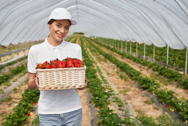 Woman posing at greenhouse with basket of strawberries