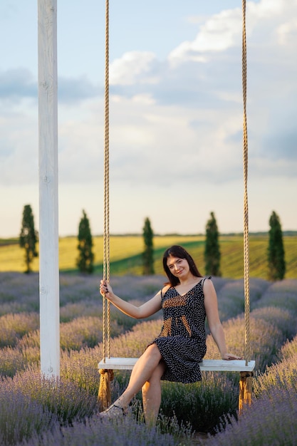 Photo woman posing on a swing in a lavender field