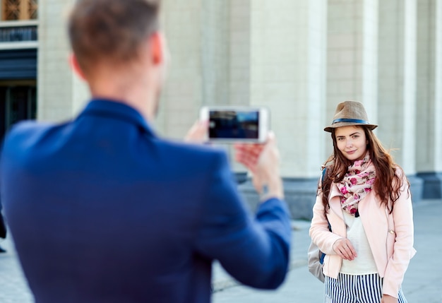 Woman posing for vacation photo in urban city tour. Couple of tourists making photo