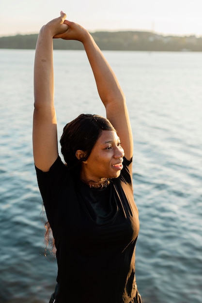 Photo woman posing while stretching by the lake