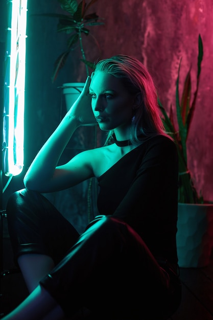 Woman posing with neon light and plants