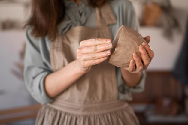 Photo woman potter at work potters hands in clay form a pot in a circle closeup female sculpting bowls from raw wet clay