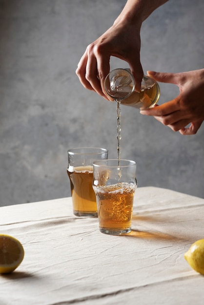 Woman pouring black hot tea in a glass, selective focus image in minimalism style