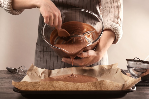 Woman pouring cacao liquid dough into baking tray