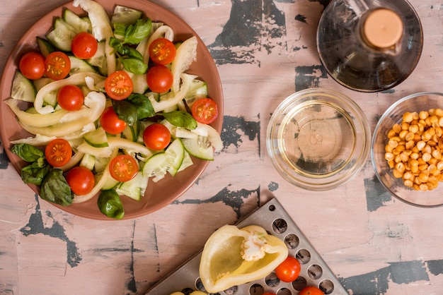 Woman pouring honey mustard dressing into bowl with fresh salad on table