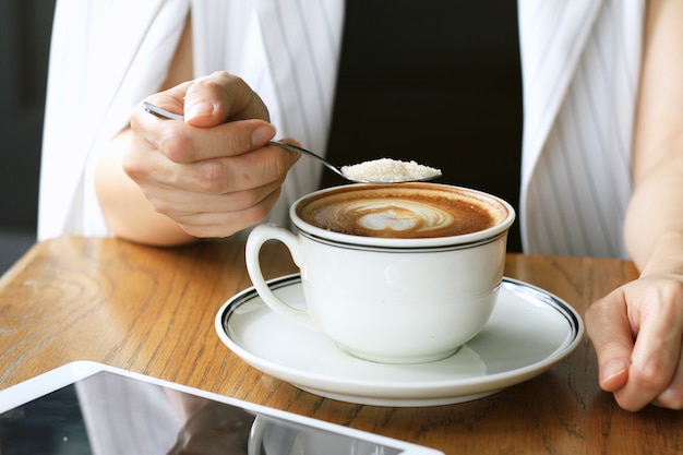 Woman pouring sugar into coffee cup. Sugar addicted concept.