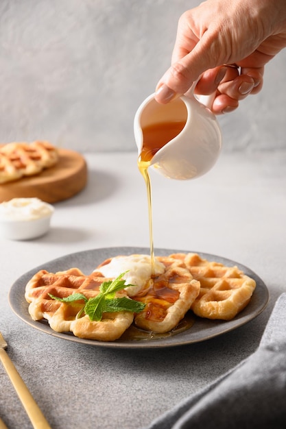 Woman pouring syrup croffles for tasty breakfast