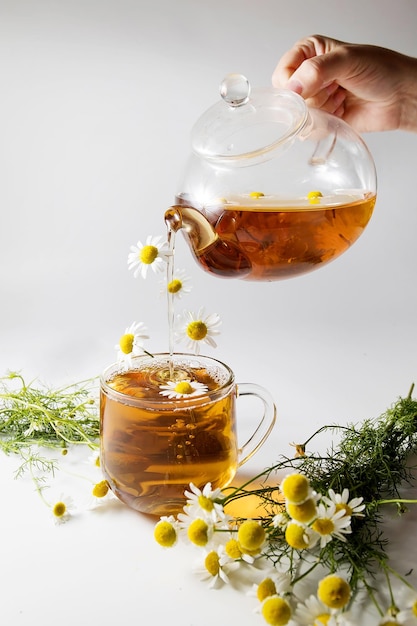 A woman pours chamomile tea into a transparent bowl a creative beautiful photo