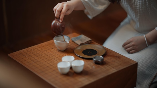 Photo a woman pours a cup of tea on a table.