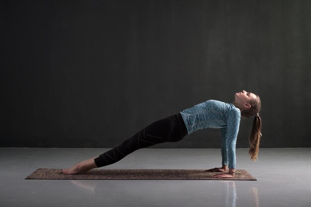 Woman practices yoga asana purvottanasana or upward facing plank