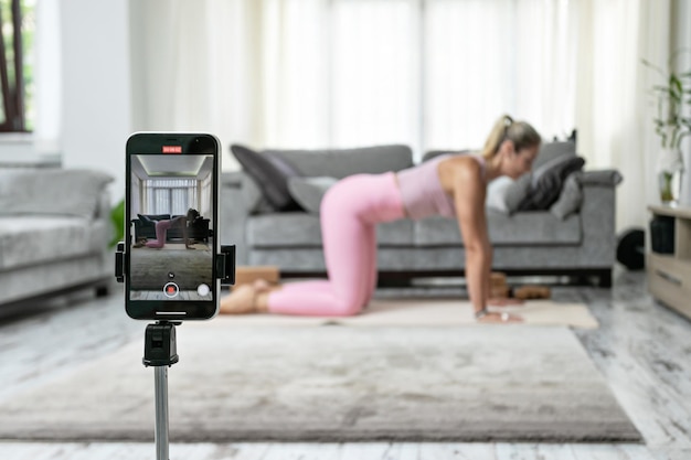 Woman practicing yoga poses stretching in front of phone camera sport blogger teacher yoga online