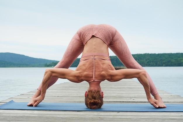 Woman practicing yoga while standing in an inverted position against the backdrop of a seascape