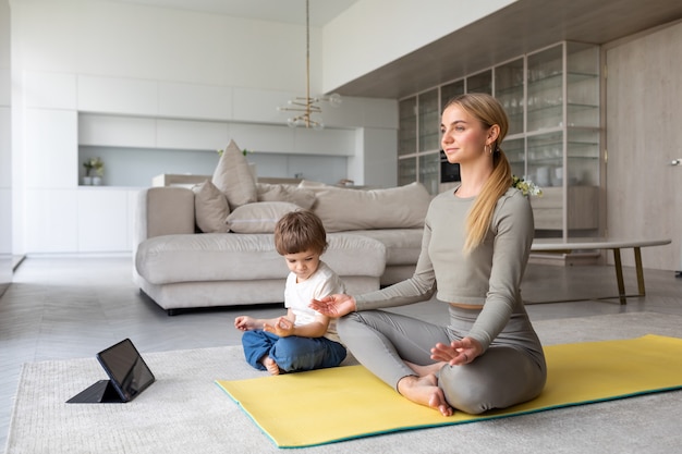 a woman practie yoga at home and child try to copy her pos