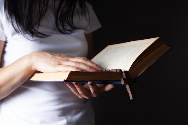 Woman praying holding book and cross