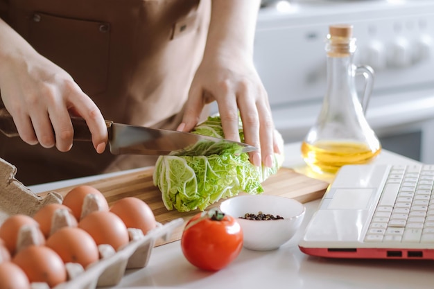 Woman prepares dietary vegetable salad at home using video recipe Online cooking lessons