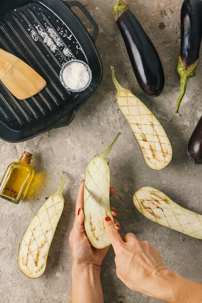 Woman prepares eggplants with vegan stuffing and pine nuts