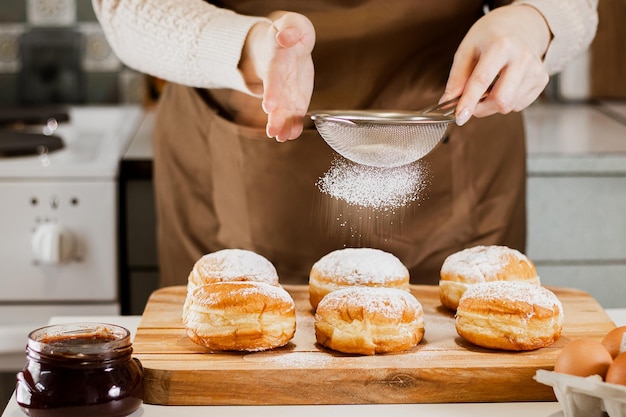 Photo woman prepares fresh donuts with jam in home kitchen cooking traditional jewish hanukkah sufganiyot