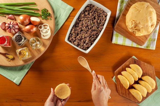 Woman preparing brazilian snacks beef stufing croquette risolis de carne Top view