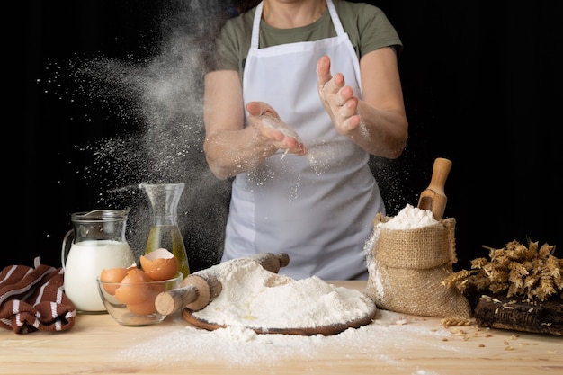 Woman preparing bread dough on a wooden table in a bakery nearby