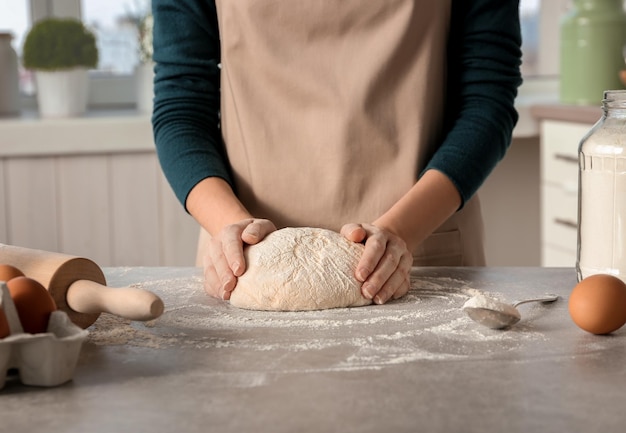 Woman preparing dough on table at kitchen